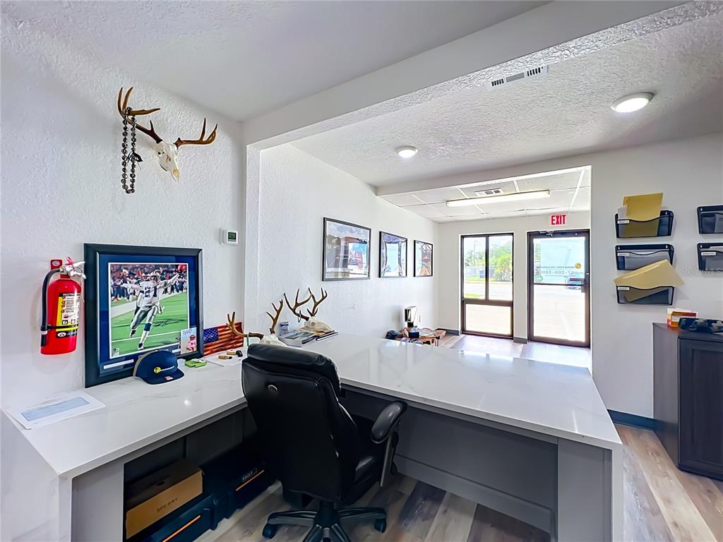 An office space features a white L-shaped desk, a black chair, and wall-mounted deer antlers — 180 S RONALD REAGAN BOULEVARD UNIT 112, LONGWOOD, FL