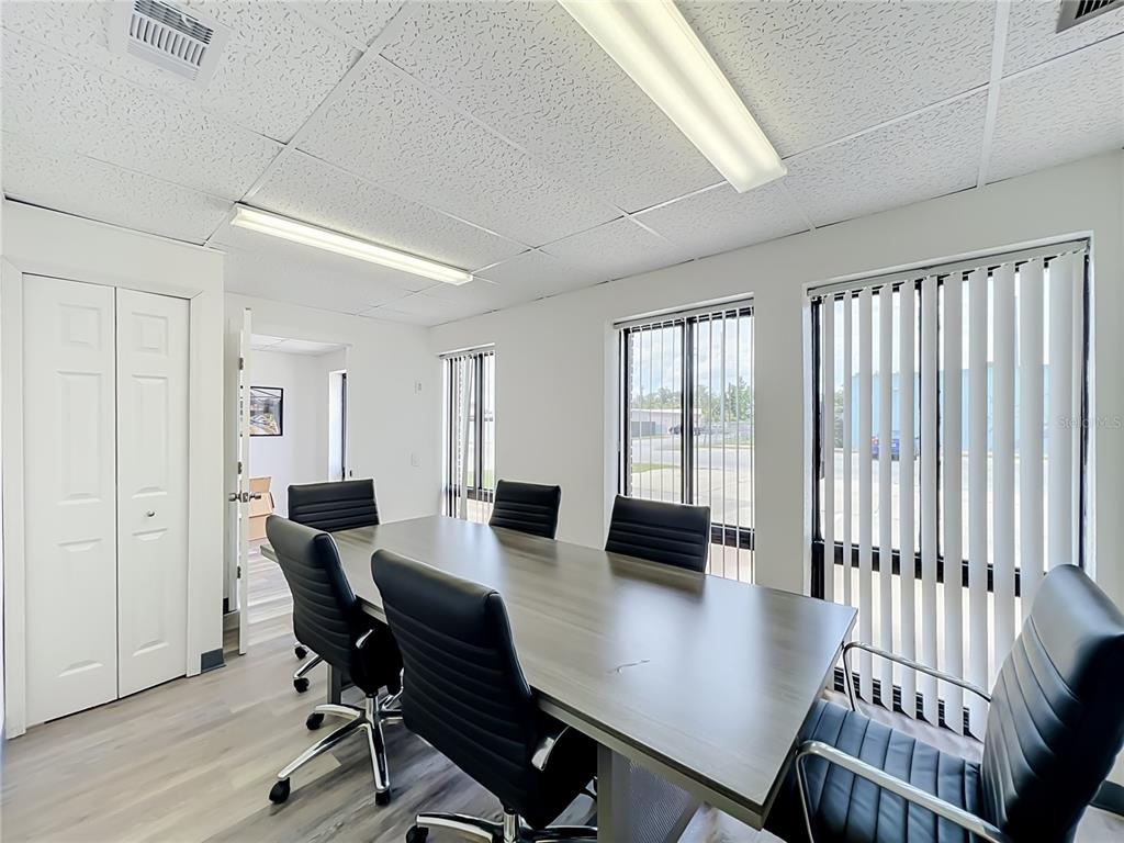 A conference room features a long table, black office chairs, vertical blinds, and drop ceilings — 180 S RONALD REAGAN BOULEVARD UNIT 112, LONGWOOD, FL