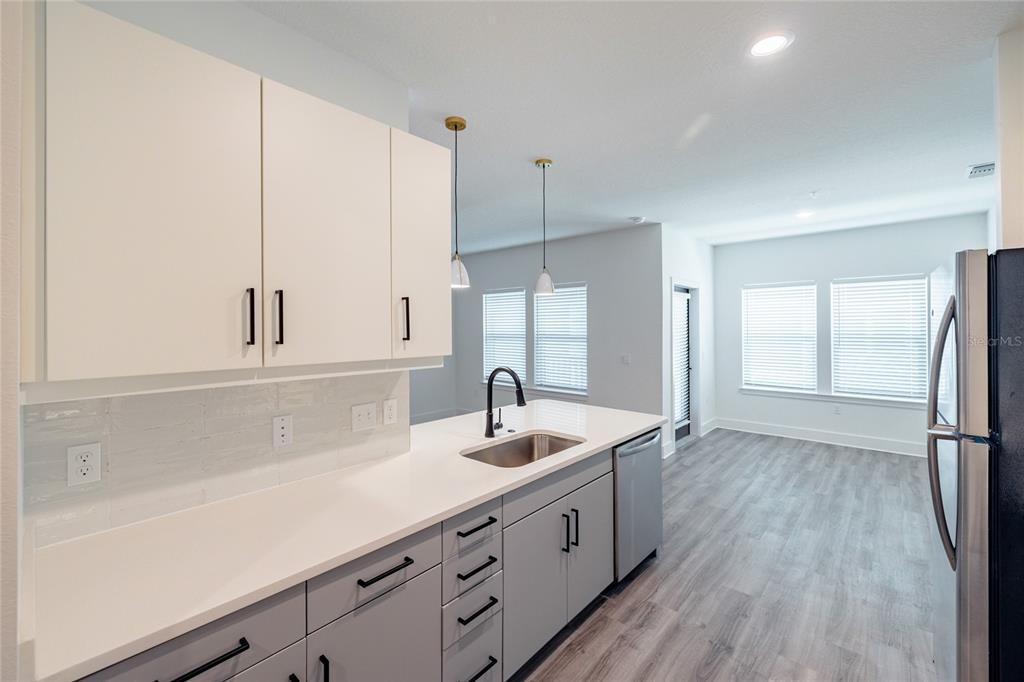 A modern kitchen features white upper cabinets, gray lower cabinets, and light wood-look flooring — 1420 LAKEFRONT DRIVE UNIT 6413, SARASOTA, FL