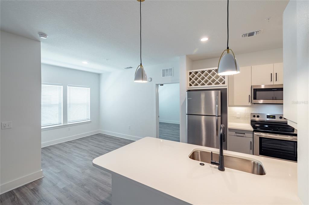 A kitchen with white cabinets, stainless steel appliances, and an island overlooks a living area — 1420 LAKEFRONT DRIVE UNIT 6413, SARASOTA, FL