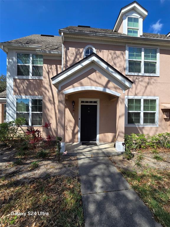 The exterior of a two-story peach-colored house features a covered entryway and a concrete walkway — 3417 WESTCHESTER SQUARE BOULEVARD UNIT 204, ORLANDO, FL