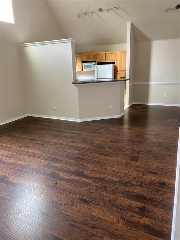 A kitchen with wood cabinets and a breakfast bar overlooks a room with wood flooring — 3417 WESTCHESTER SQUARE BOULEVARD UNIT 204, ORLANDO, FL