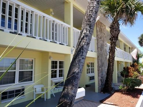 A multi-story yellow building with balconies, a stone pillar, and a palm tree in front — 1700 S ATLANTIC AVENUE, DAYTONA BEACH, FL