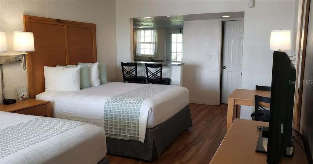 A hotel room features two beds, a small dining area, and a kitchenette with stools — 1700 S ATLANTIC AVENUE, DAYTONA BEACH, FL