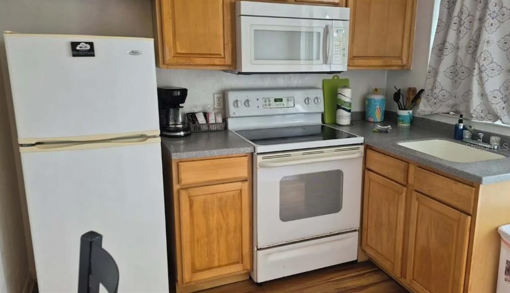 A kitchen features light wood cabinets, white appliances, and a gray countertop — 1700 S ATLANTIC AVENUE, DAYTONA BEACH, FL