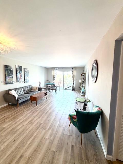 A living room with wood-look tile flooring, a gray sofa, and a green accent chair — 215 SE 3rd Ave # 306C, Hallandale Beach FL 33009, HALLANDALE BEACH, FL