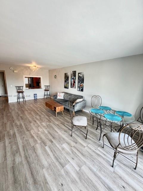 This open-concept living and dining area features light wood-look flooring and a grey sofa — 215 SE 3rd Ave # 306C, Hallandale Beach FL 33009, HALLANDALE BEACH, FL
