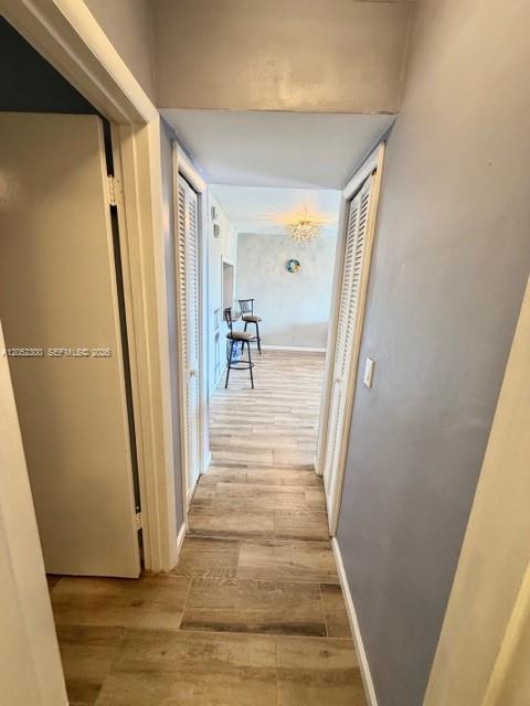 A hallway with light wood-look flooring leads to a room with bar stools and lighting — 215 SE 3rd Ave # 306C, Hallandale Beach FL 33009, HALLANDALE BEACH, FL