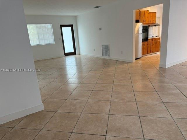 An open-concept living area features light-colored tile flooring and a view into a kitchen — 753 Navarre Ave, Coral Gables FL 33134, CORAL GABLES, FL