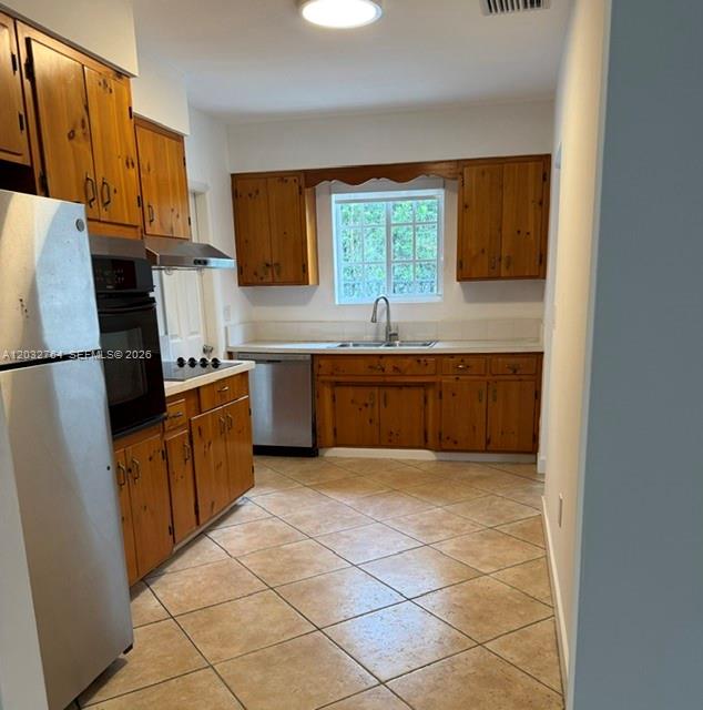 A kitchen features wooden cabinets, a stainless steel dishwasher, a wall oven, and tiled floors — 753 Navarre Ave, Coral Gables FL 33134, CORAL GABLES, FL