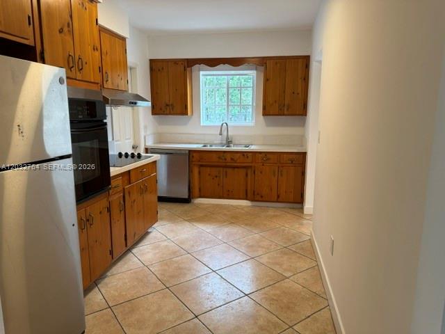 A kitchen features wood cabinets, tile flooring, a stainless steel refrigerator, and a window — 753 Navarre Ave, Coral Gables FL 33134, CORAL GABLES, FL