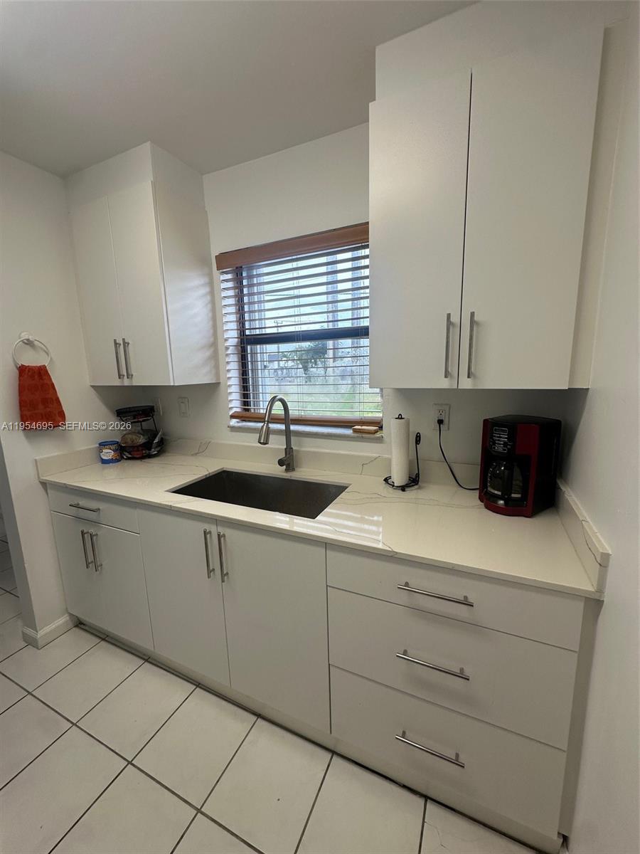 A kitchen features white cabinets, a light-colored countertop, a stainless steel sink, and tile flooring — 13671 SW 62nd St # 1, Miami FL 33183, MIAMI, FL