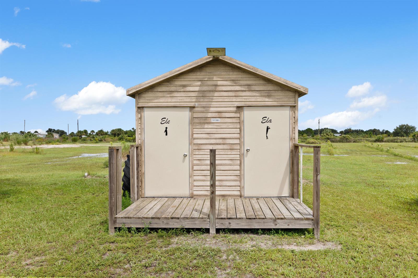A small wooden shed with two doors labeled Ele and Ela stands on a wooden deck — 20914 NW 280th Street, Okeechobee FL 34972, OKEECHOBEE, FL