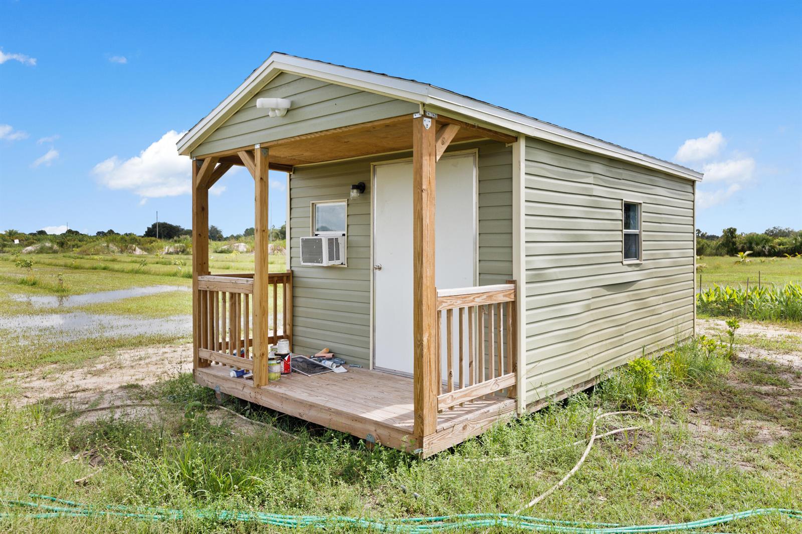 A small, light green shed with a front porch sits in a grassy, open field — 20914 NW 280th Street, Okeechobee FL 34972, OKEECHOBEE, FL