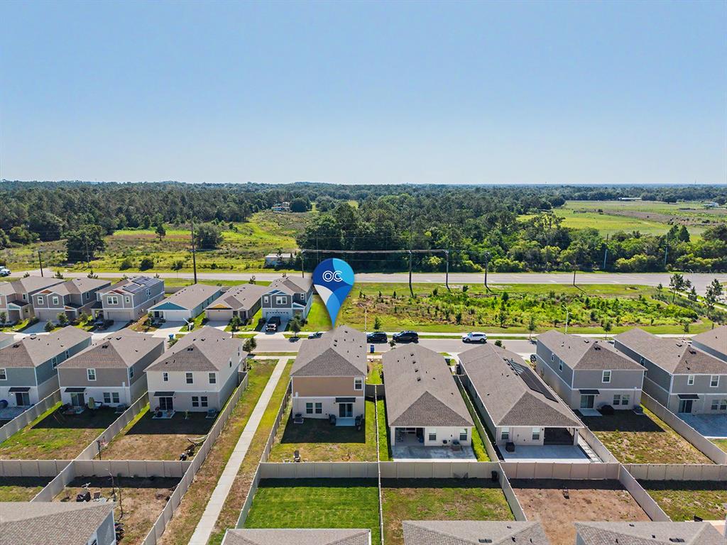 An aerial view shows the rear exterior of a suburban house with a fenced backyard — 7587 STARFLOWER WAY, WESLEY CHAPEL, FL