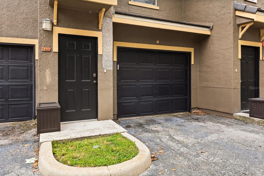 The exterior of a townhouse features a black front door, a garage, and a small planter — 179 VILLA DI ESTE TERRACE UNIT 201, LAKE MARY, FL