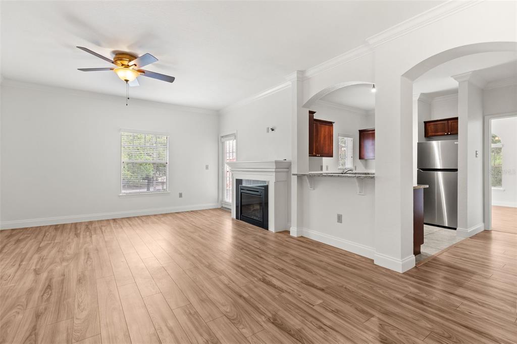 A living room with light wood flooring, a fireplace, and an open kitchen with stainless appliances — 179 VILLA DI ESTE TERRACE UNIT 201, LAKE MARY, FL