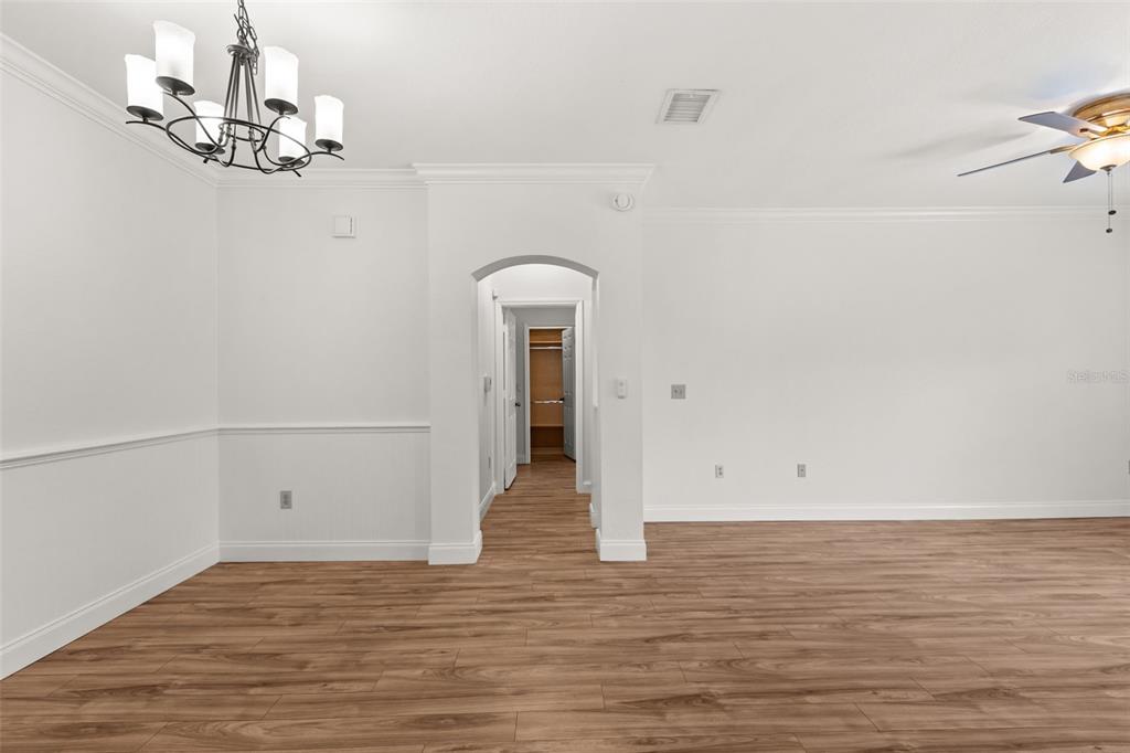 An interior room with wood-look flooring, white walls, a chandelier, and an arched hallway entrance — 179 VILLA DI ESTE TERRACE UNIT 201, LAKE MARY, FL