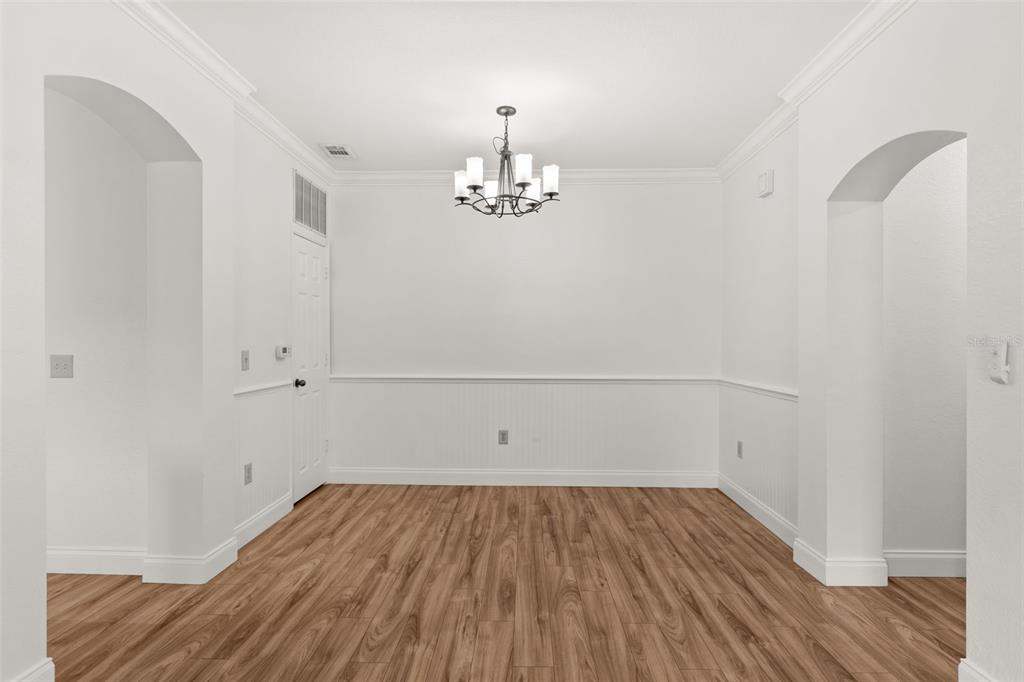 A dining room with white walls, wainscoting, a chandelier, and wood-look flooring — 179 VILLA DI ESTE TERRACE UNIT 201, LAKE MARY, FL