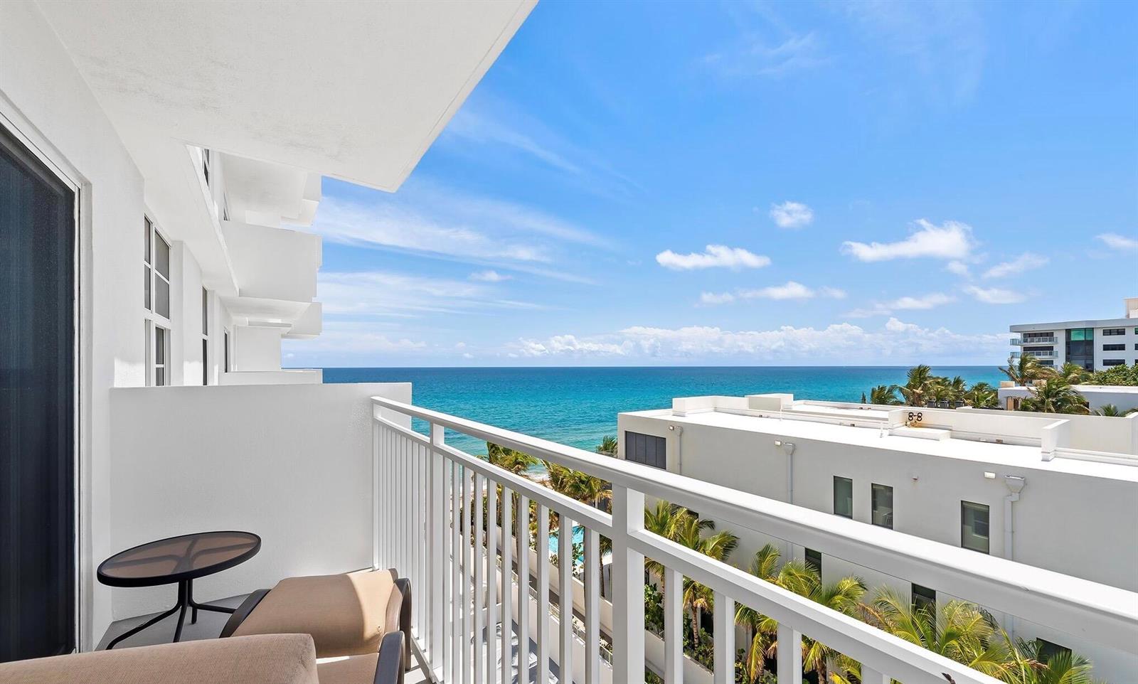 A balcony with a small table and chairs overlooks the ocean and nearby buildings — 4511 S Ocean Boulevard # 601, Highland Beach FL 33487, HIGHLAND BEACH, FL