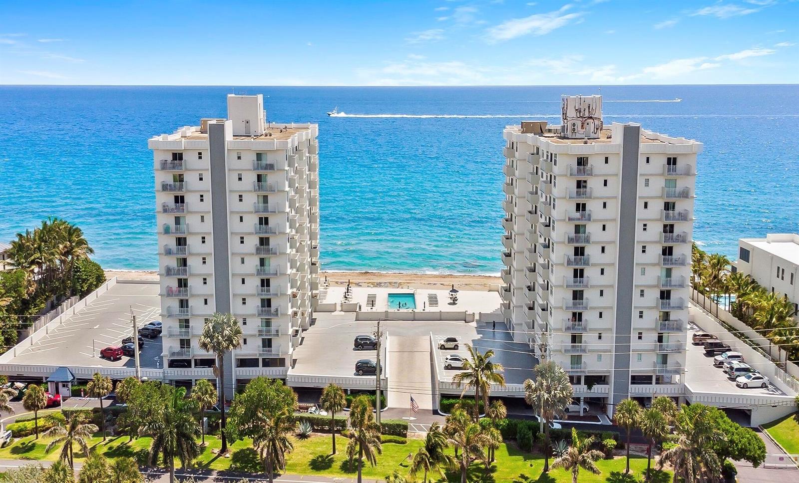 An aerial view shows two tall residential buildings situated directly on a sandy beach — 4511 S Ocean Boulevard # 601, Highland Beach FL 33487, HIGHLAND BEACH, FL