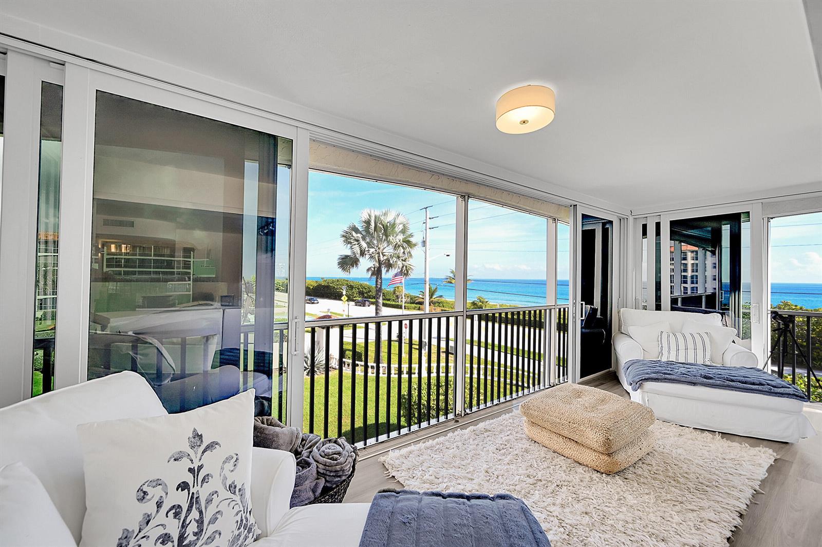A sunroom features white furniture, a shaggy rug, and sliding glass doors overlooking the ocean — 2871 N Ocean Boulevard # D302, Boca Raton FL 33431, BOCA RATON, FL