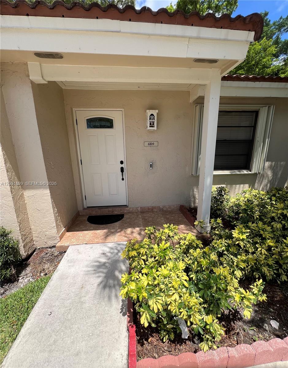 The exterior view shows a covered entryway with a white door and tiled porch — 6109 NW 171st St, Hialeah FL 33015, HIALEAH, FL