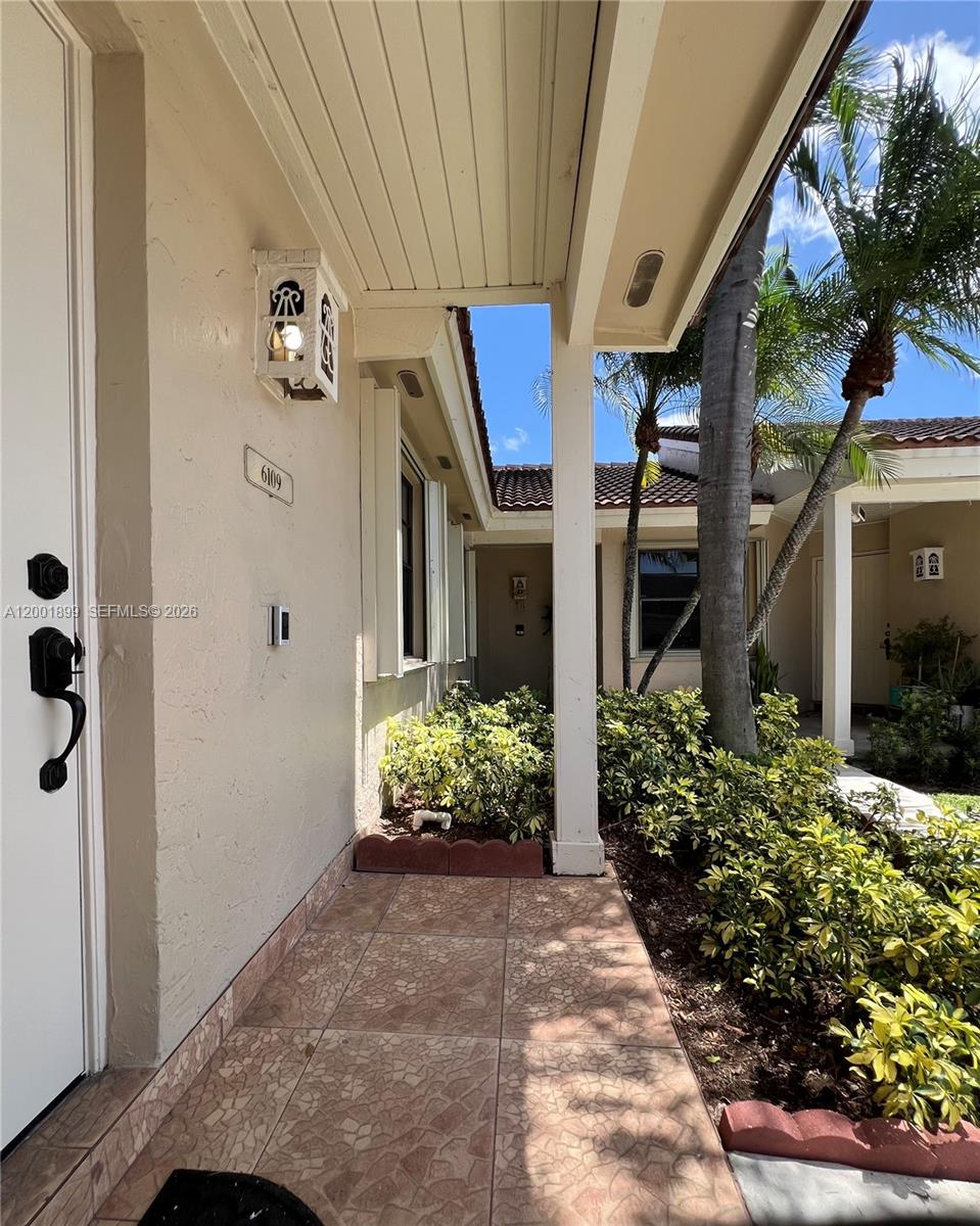 A tiled entryway leads to a front door with a light fixture and landscaping — 6109 NW 171st St, Hialeah FL 33015, HIALEAH, FL