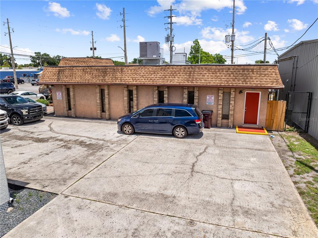 A single-story commercial building with a brown shingled roof and a red exterior door — 1211 12TH STREET, ST CLOUD, FL