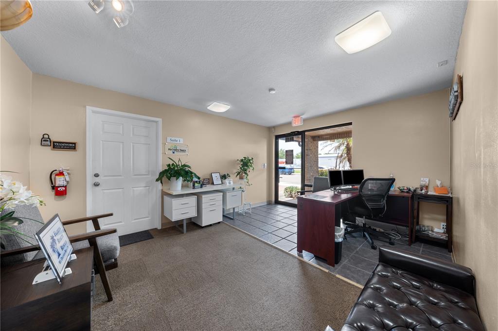 A small office reception area features a desk, seating, and a white entrance door — 1211 12TH STREET, ST CLOUD, FL