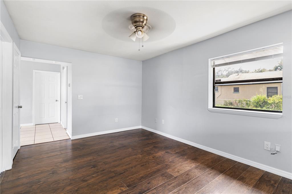 An empty bedroom with light gray walls, dark wood-look flooring, a ceiling fan, and a window — 638 W 8TH STREET, LAKELAND, FL