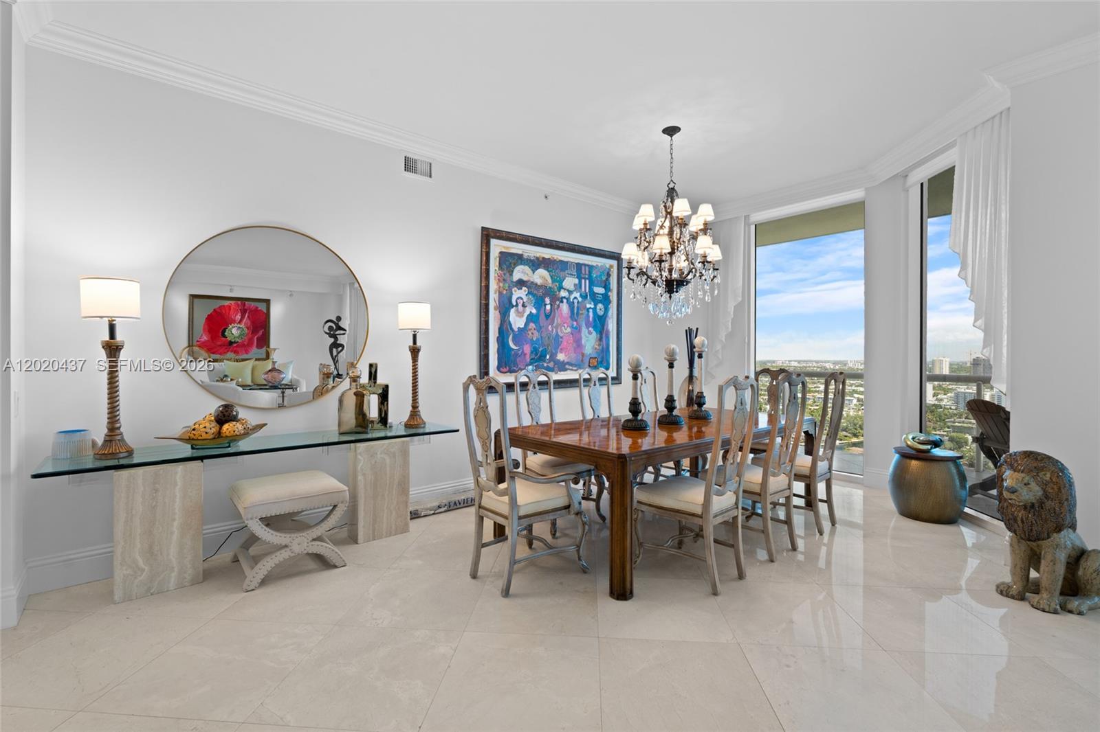 A dining room features a wooden table, chandelier, large mirror, and floor-to-ceiling windows — 21200 Point Pl # 2802, Aventura FL 33180, AVENTURA, FL