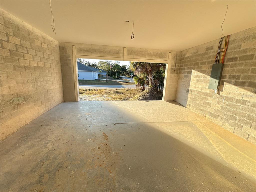 An unfinished garage with exposed concrete block walls, a concrete floor, and no door — 34 LONGLEY DRIVE, PORT CHARLOTTE, FL