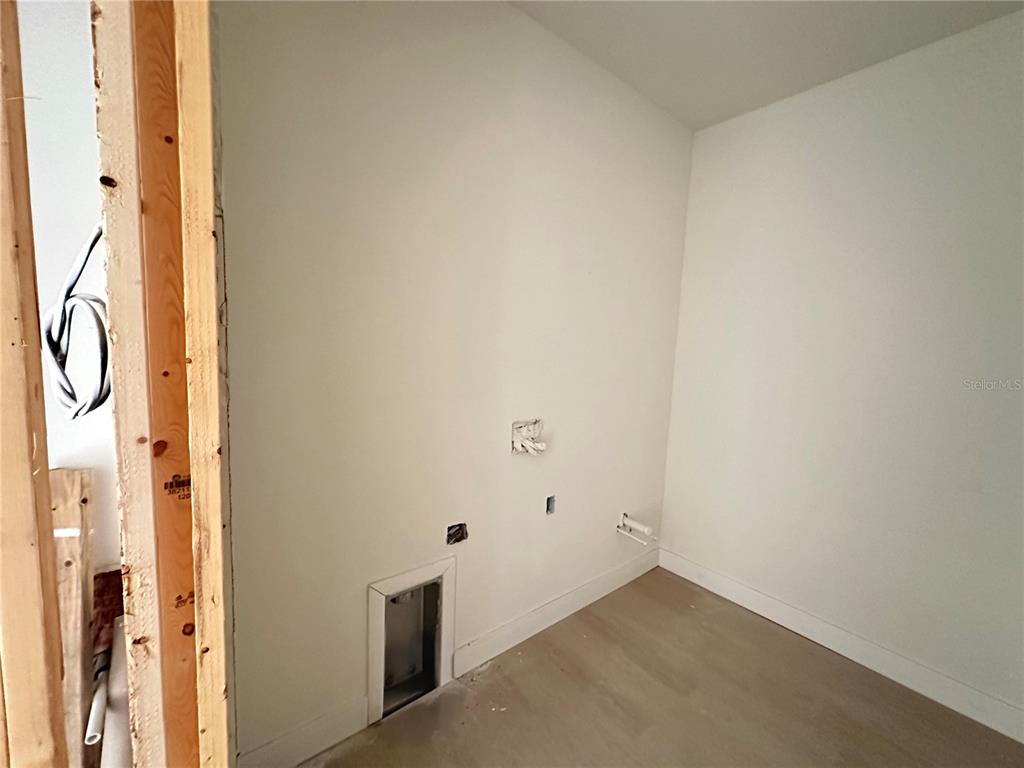 An unfinished laundry room features exposed wall studs, plumbing hookups, and light-colored wood flooring — 34 LONGLEY DRIVE, PORT CHARLOTTE, FL