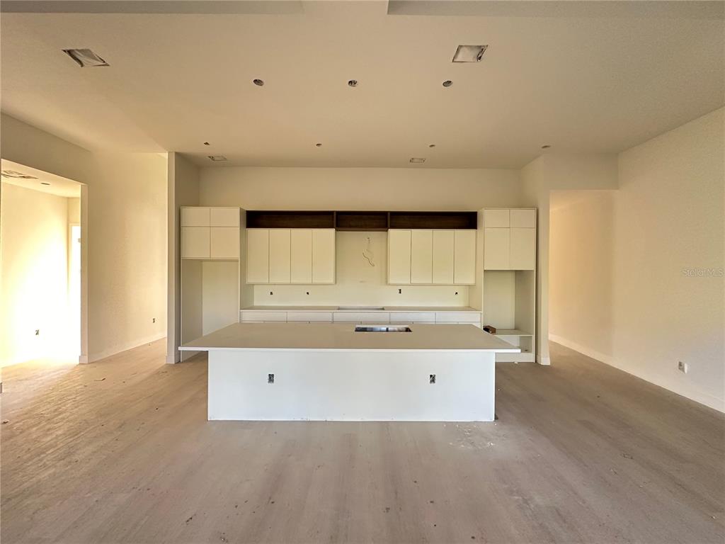 A modern kitchen features white cabinetry, a large central island, and light wood flooring — 34 LONGLEY DRIVE, PORT CHARLOTTE, FL