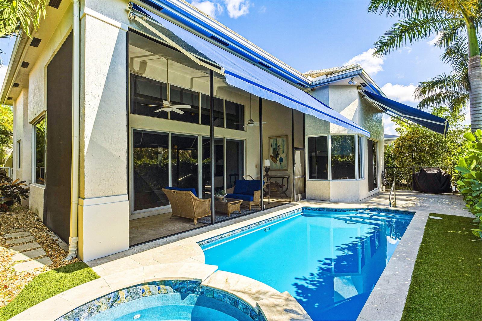 A swimming pool and hot tub sit outside a home with a screened-in patio area — 7011 Islegrove Place, Boca Raton FL 33433, BOCA RATON, FL