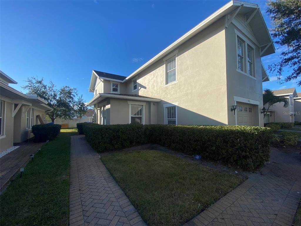 A two-story beige house with a brick walkway and a manicured hedge in the front — 2076 CYPRESS BAY BOULEVARD, KISSIMMEE, FL