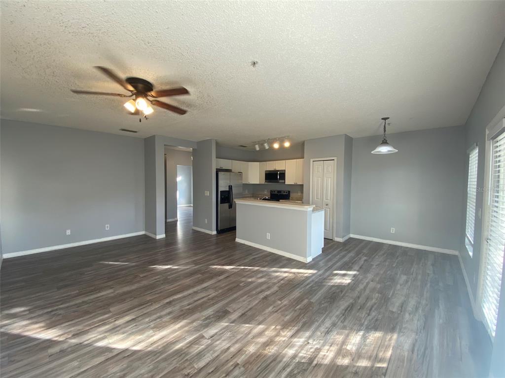 An open-concept living and dining area features gray walls, wood-look flooring, and a kitchen island — 2076 CYPRESS BAY BOULEVARD, KISSIMMEE, FL