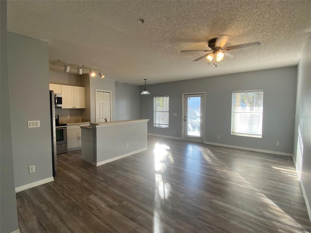 An open-concept living area features light gray walls, wood-look flooring, and an adjacent kitchen — 2076 CYPRESS BAY BOULEVARD, KISSIMMEE, FL