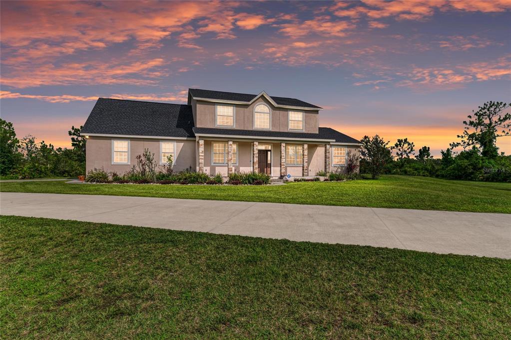 A two-story house with a stucco exterior, stone accents, and a large front lawn — 8331 241ST STREET E, MYAKKA CITY, FL
