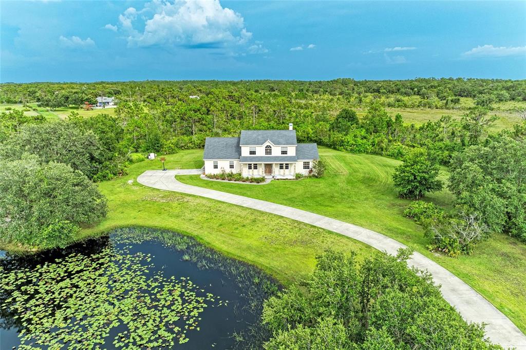 An aerial view shows a two-story house with a long driveway and a lily-covered pond — 8331 241ST STREET E, MYAKKA CITY, FL