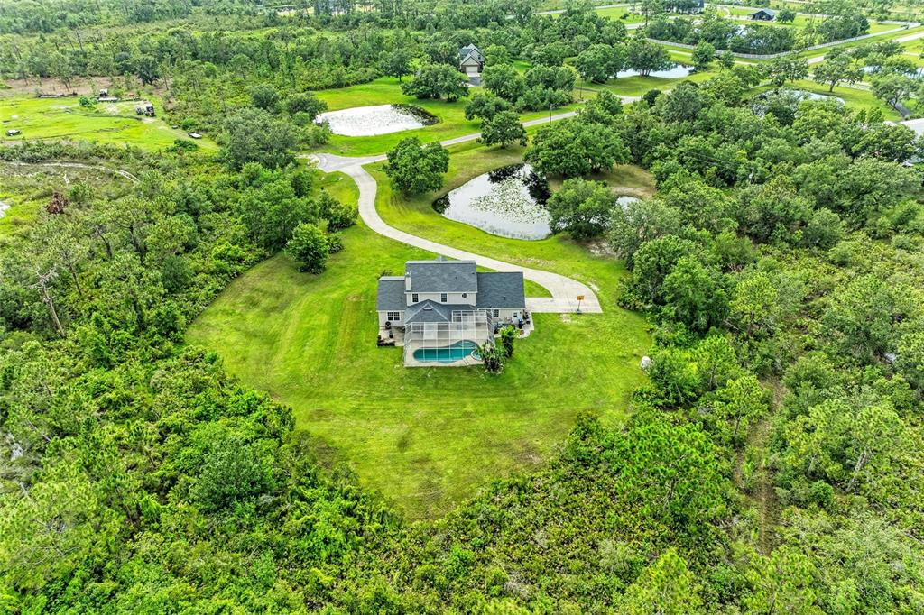 An aerial view of a house with a pool surrounded by trees and ponds — 8331 241ST STREET E, MYAKKA CITY, FL