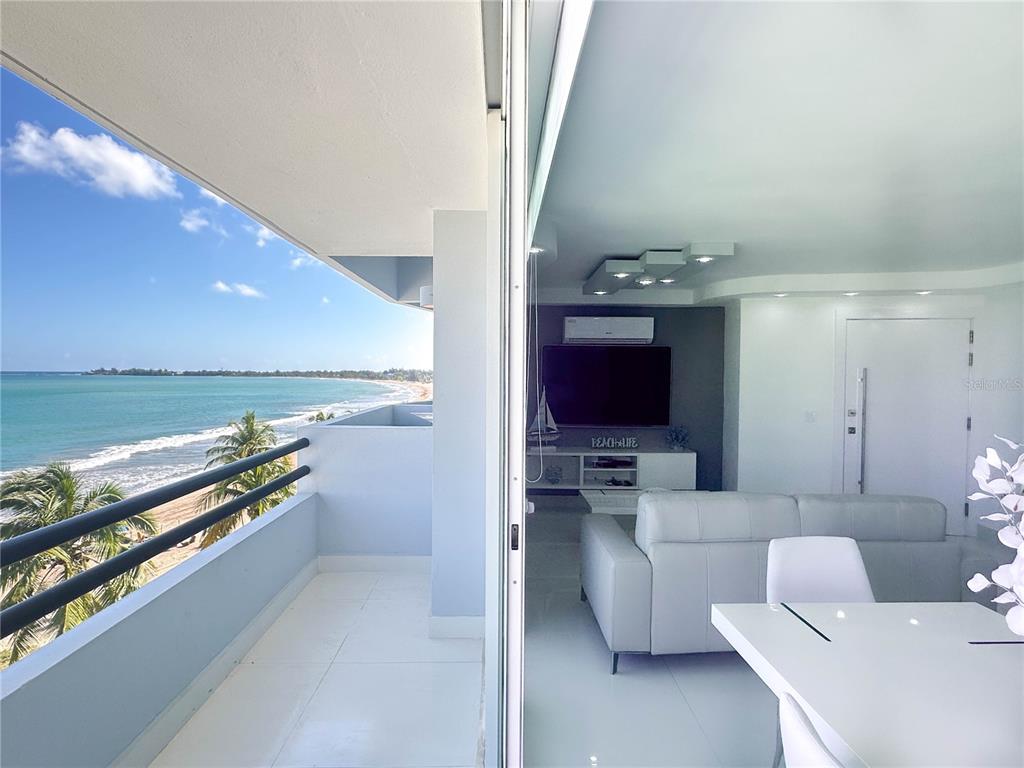 A modern living room with a white sofa overlooks a balcony and the ocean — 7043 Horizonte St. PLAYA DORADA UNIT 602A, CAROLINA, PR