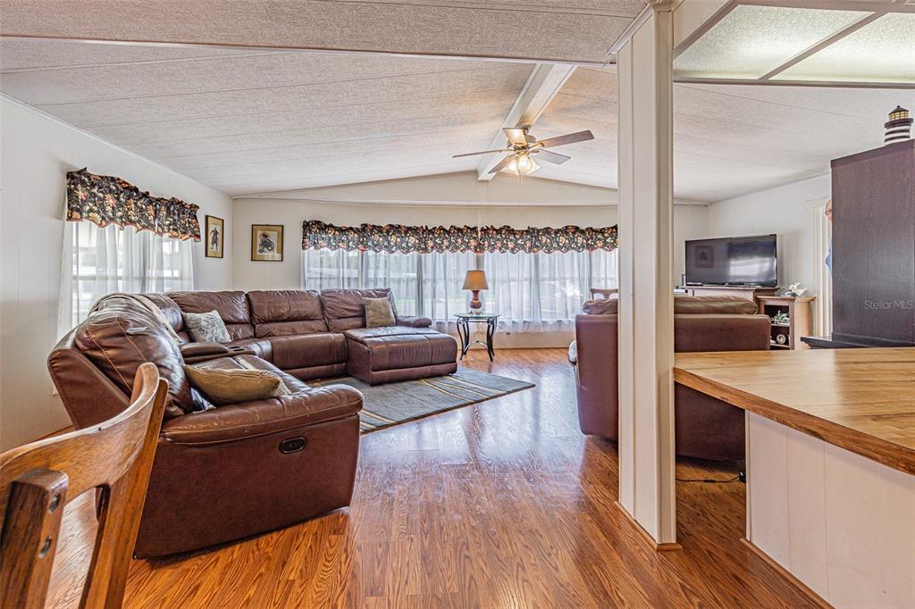 A living room features a large brown sectional sofa, wood-look flooring, and a ceiling fan — 39353 SYCAMORE LANE, ZEPHYRHILLS, FL