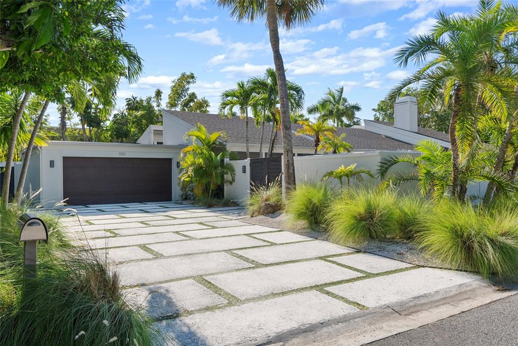 A modern house with a paved driveway, garage, and palm trees under a blue sky — 1100 WESTWAY DRIVE, SARASOTA, FL