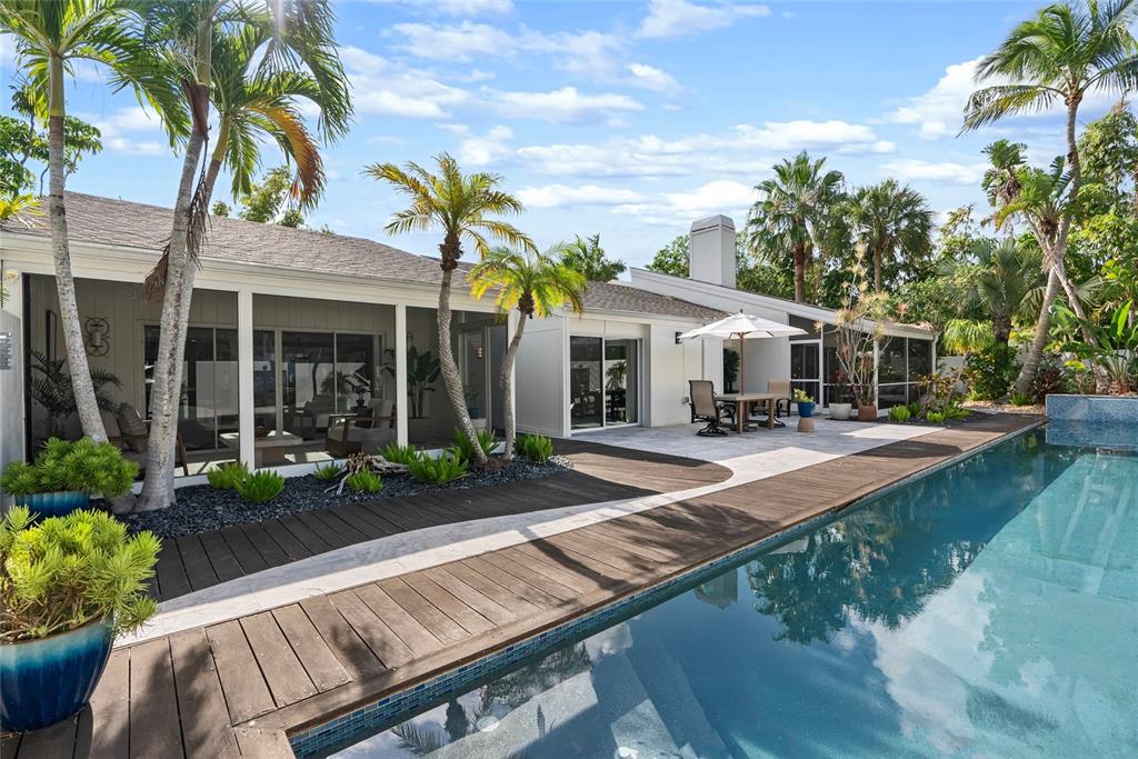 A swimming pool with a wooden deck sits beside a house with a covered patio — 1100 WESTWAY DRIVE, SARASOTA, FL