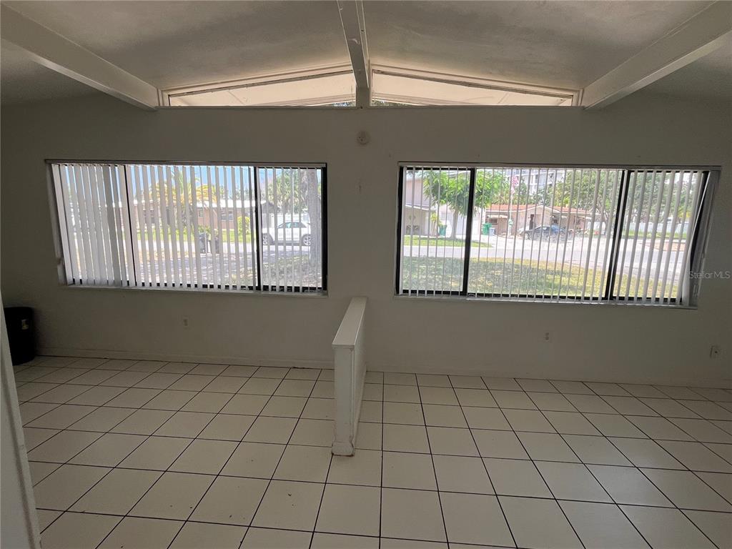 A room with white tile floors, two large windows with vertical blinds, and a half wall — 813 8TH STREET, MERRITT ISLAND, FL
