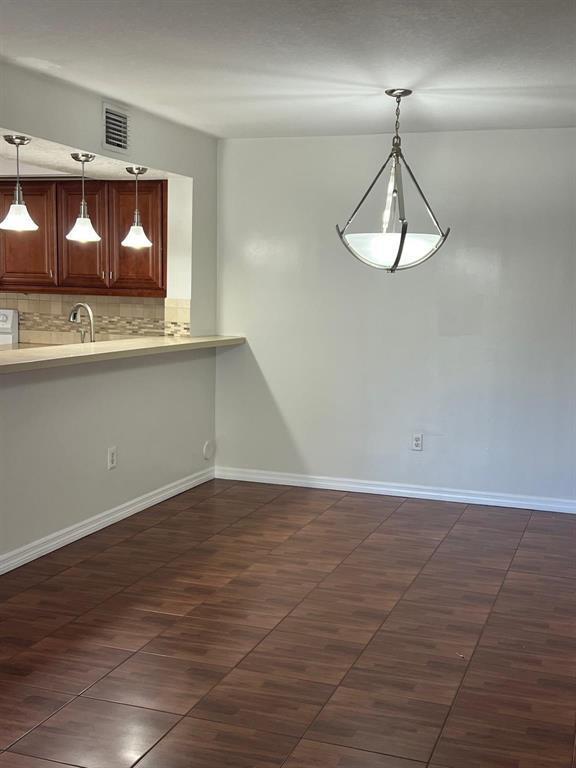 A dining area with wood-look tile flooring, a pendant light, and a kitchen breakfast bar — 18840 NW 57th Avenue Unit 101, Hialeah FL 33015, HIALEAH, FL
