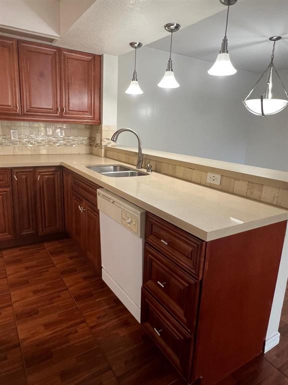 A kitchen features wood cabinets, a light-colored countertop, a stainless steel sink, and pendant lighting — 18840 NW 57th Avenue Unit 101, Hialeah FL 33015, HIALEAH, FL