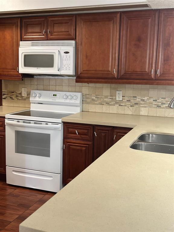 A kitchen features wood cabinets, white appliances, a light-colored countertop, and a tiled backsplash — 18840 NW 57th Avenue Unit 101, Hialeah FL 33015, HIALEAH, FL